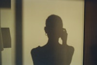 a shadow of a woman talking on a cell phone