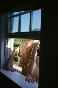 a naked woman looking out of a window